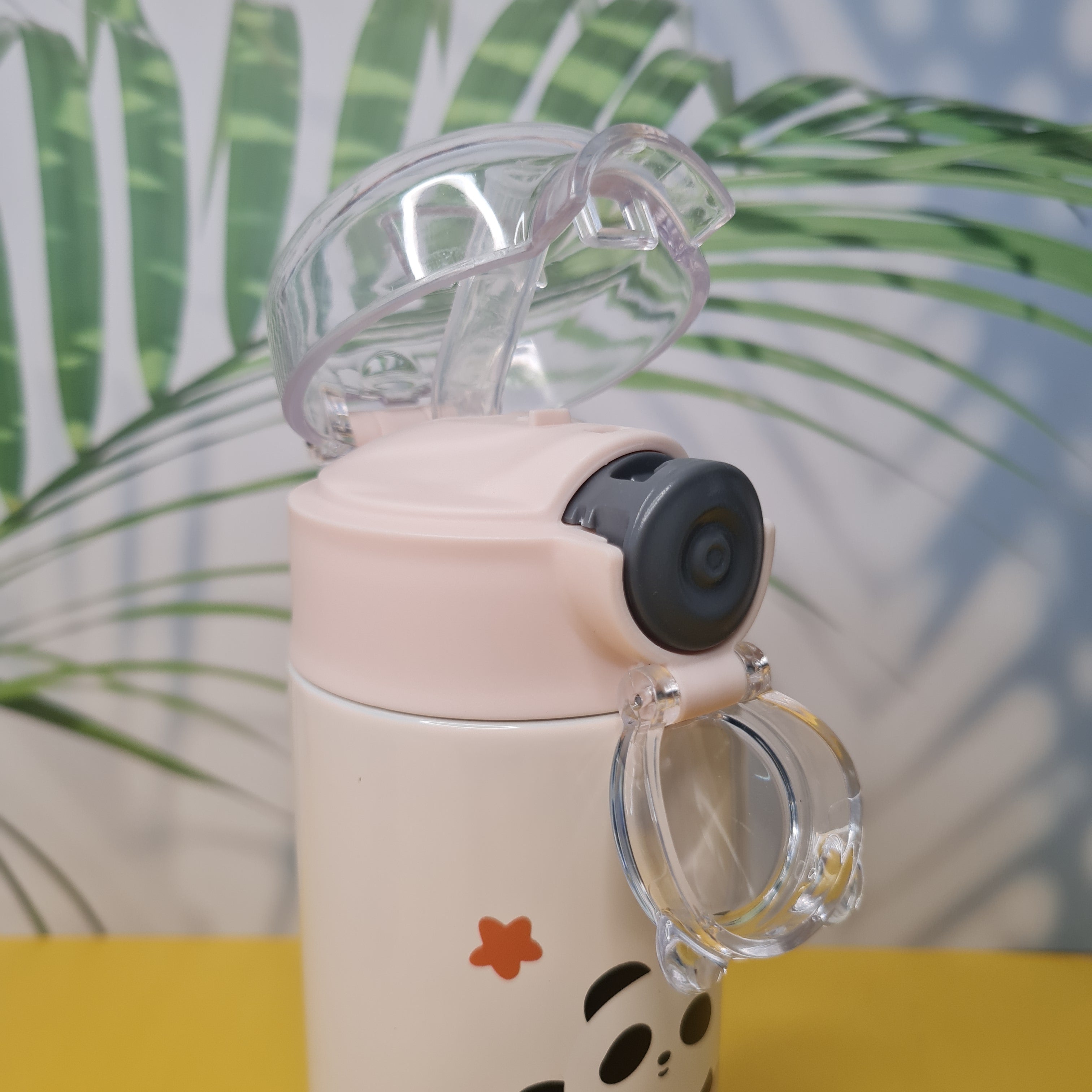Pink water bottle with clear lid and black cap on a blurred natural background